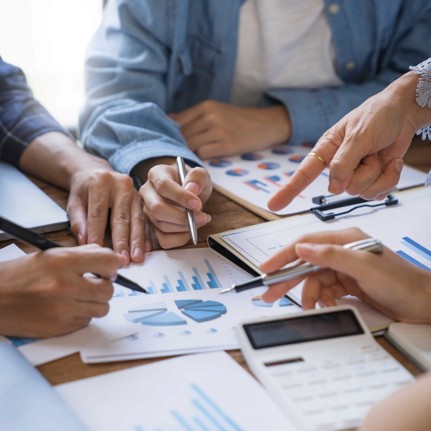 a group of people pointing at several pictures of graphs on paper